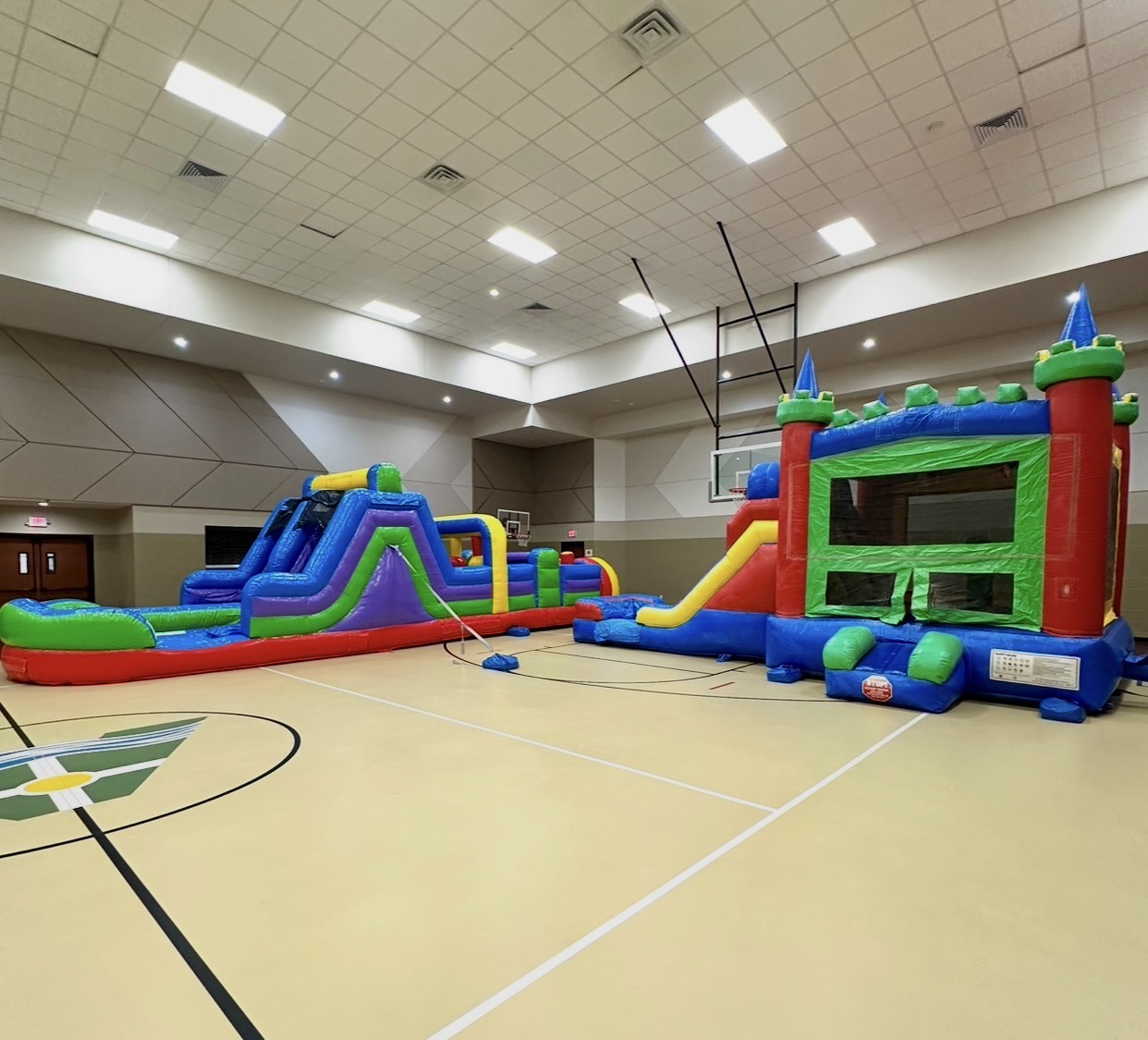 Bounce house and inflatable obstacle course set up for an indoor Houston event